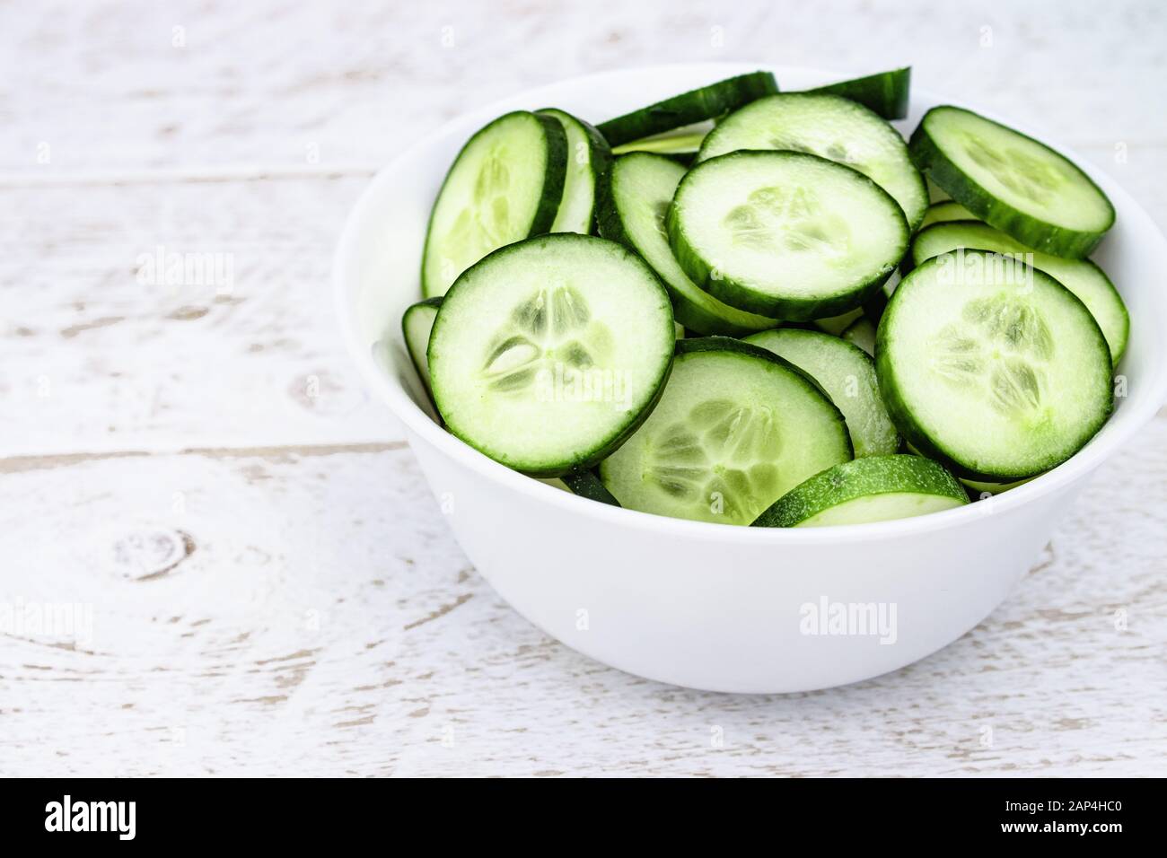 In Scheiben geschnittene Ringe aus grünen Gurken in einer weißen Platte auf weißem Grund. Nahaufnahme. Stockfoto