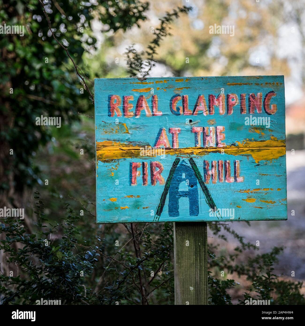 Eine handbemalte Werbung sign ein glamping Website in Colan Woods, der überwucherte Gelände des historischen Tanne Hill Manor in Colan Pfarrei in Newquay in Cor Stockfoto