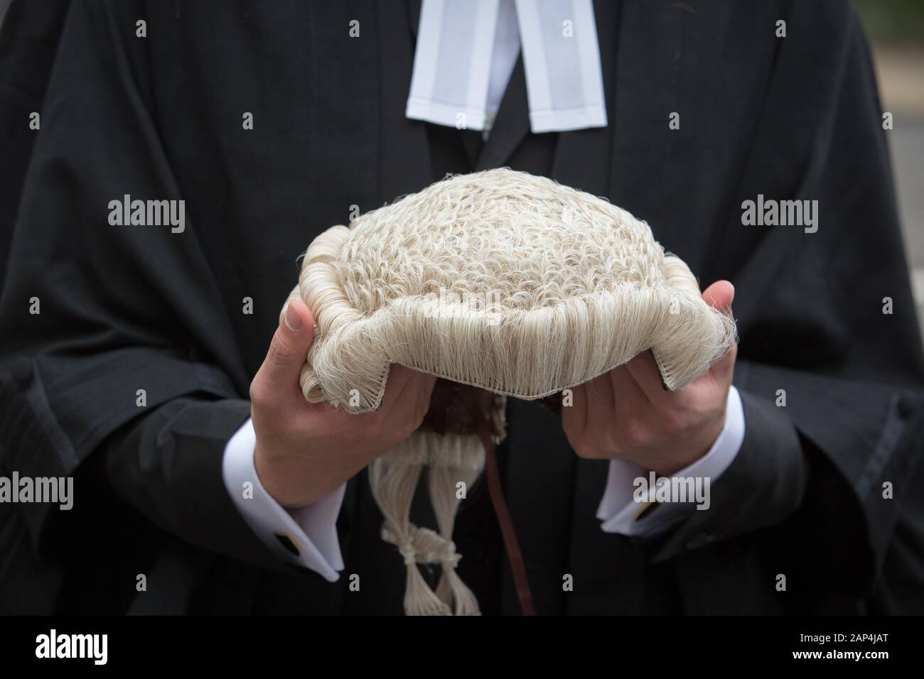 Ein Mann, der eine legale Kleidung trägt und eine Gerichtsperücke hält, die sonst als Peruke bekannt ist Stockfoto