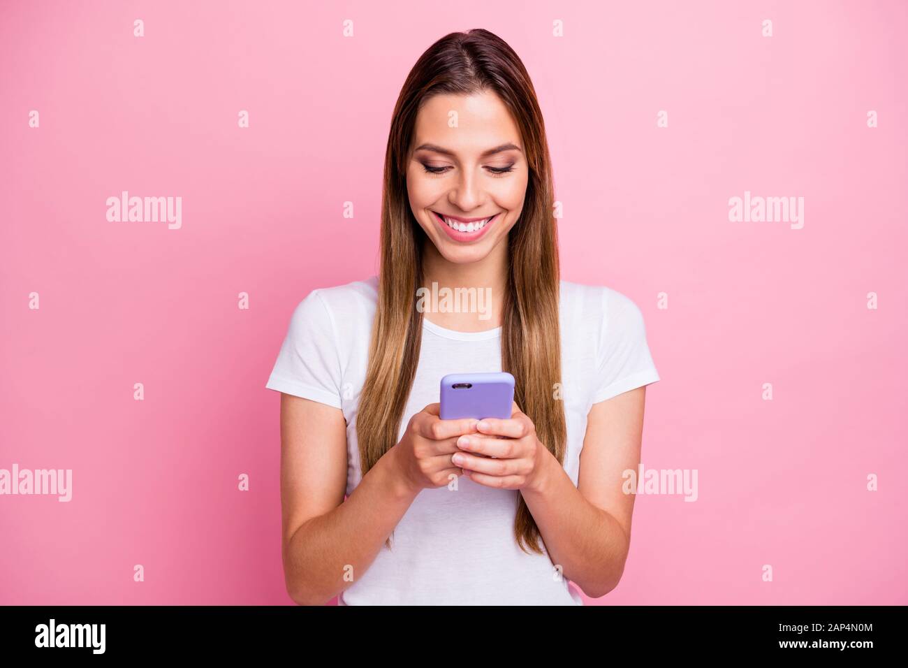 Welches Bild am besten ist. Foto der hübschen Dame, die Telefonhände hält, SMS-Freunde, die neue gerade gemachte Selfies schicken, tragen legere weiße T-Shirts isoliert Stockfoto