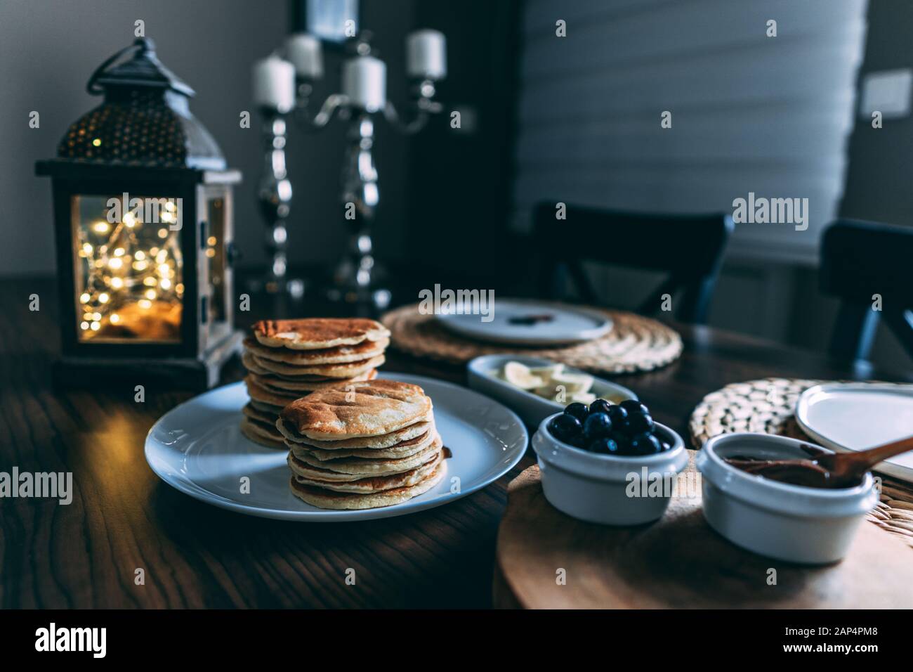 Pfannkuchen mit frischer Heidelbeere und Himbeere. Serviert auf dem mit Lichtern dekorierten Tisch Stockfoto