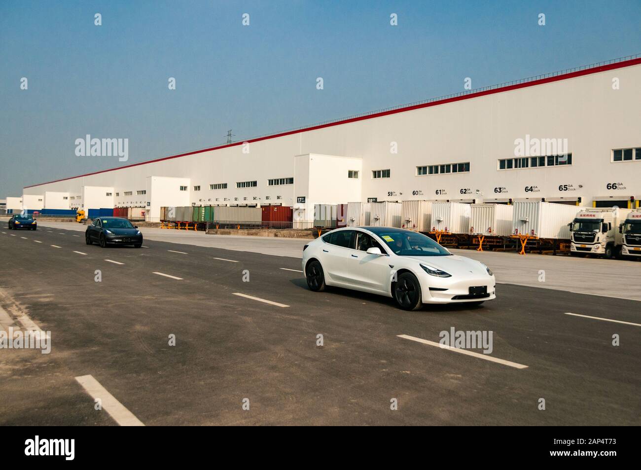 Eine Reihe Chinesen ließen Tesla Model 3s an der neuen Tesla-Fabrik in Lingang, Shanghai vorbeifahren. Stockfoto
