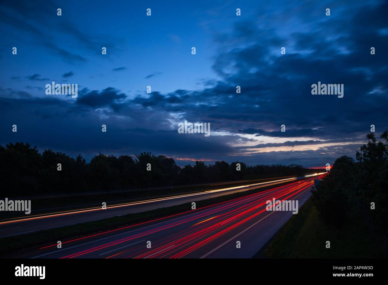 Dramatischer Abendhimmel über Landstraße oder Autobahn mit dem Auto Licht Wanderwege in der Nacht, Langzeitbelichtung Schuss Stockfoto