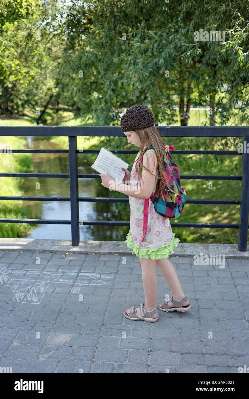 Mädchen, die ein Buch lesen, während sie über die Brücke laufen Stockfoto