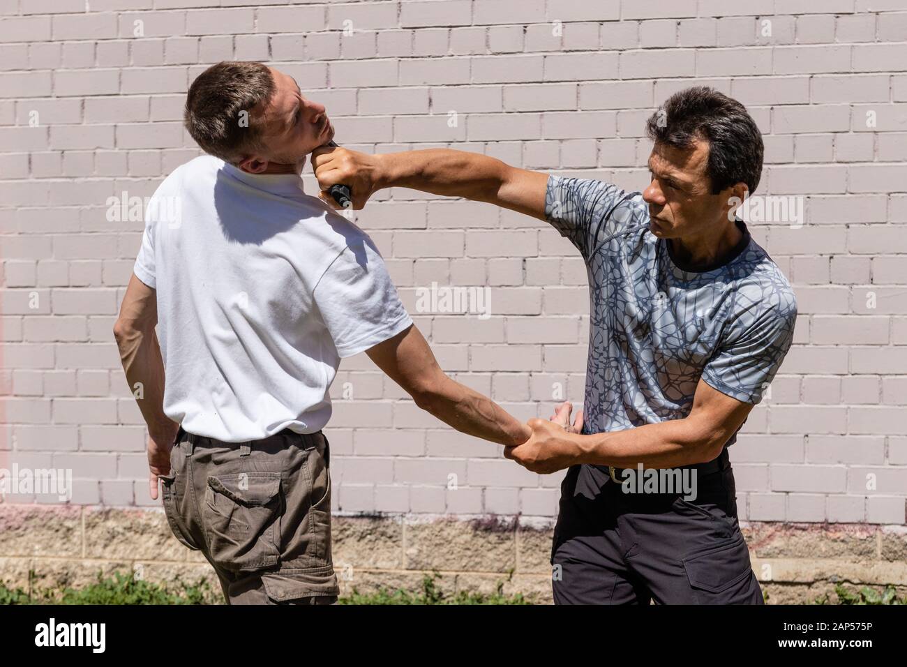 Verteidiger verteidigt sich mit einer Waffe gegen den Angreifer. Ein Mann schlägt dem Aggressor mit einer Pistole entgegen, die er ihm abnahm. Nahaufnahme. Selbstverteidigung Techniq Stockfoto