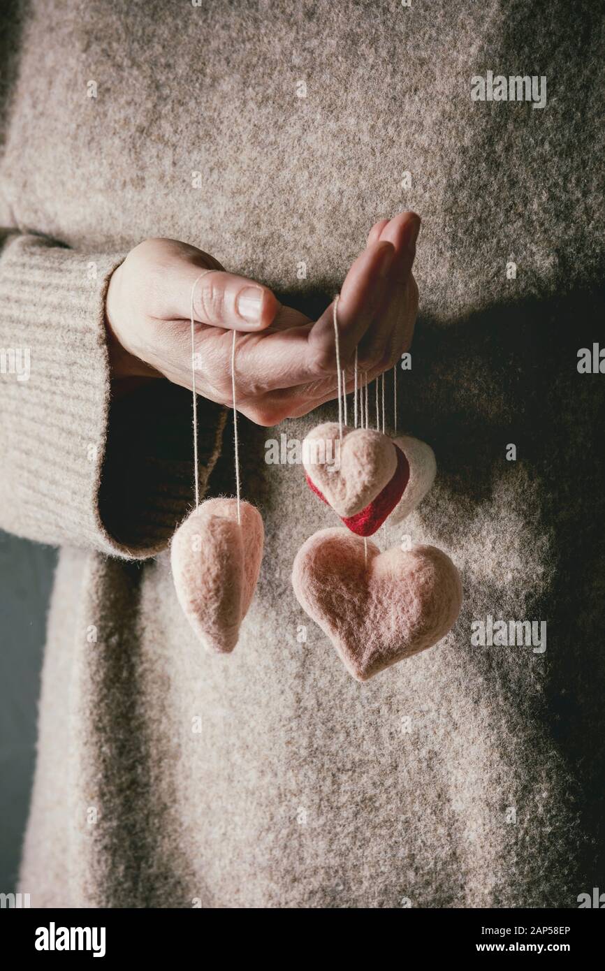 Frau in Kaschmir Pullover halten Sie in Händen der Nadel gefilzte Herzen auf den Gewinden. St Valentines Tag Grußkarte Stockfoto