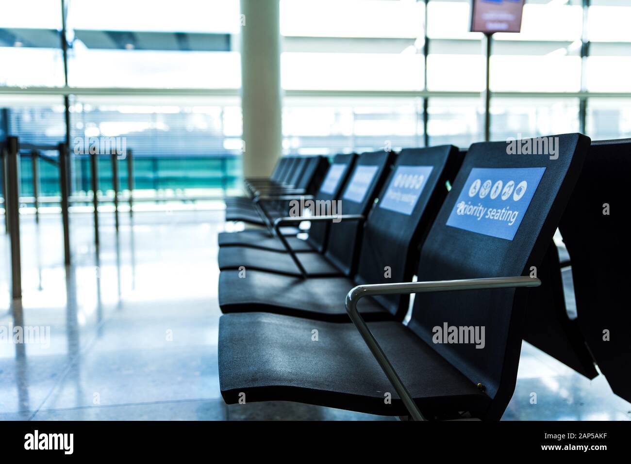 Leere Prioritätssitze an einem Flughafen im Wartebereich vor dem Einsteigen. Blaue Schilder auf Stühlen Stockfoto