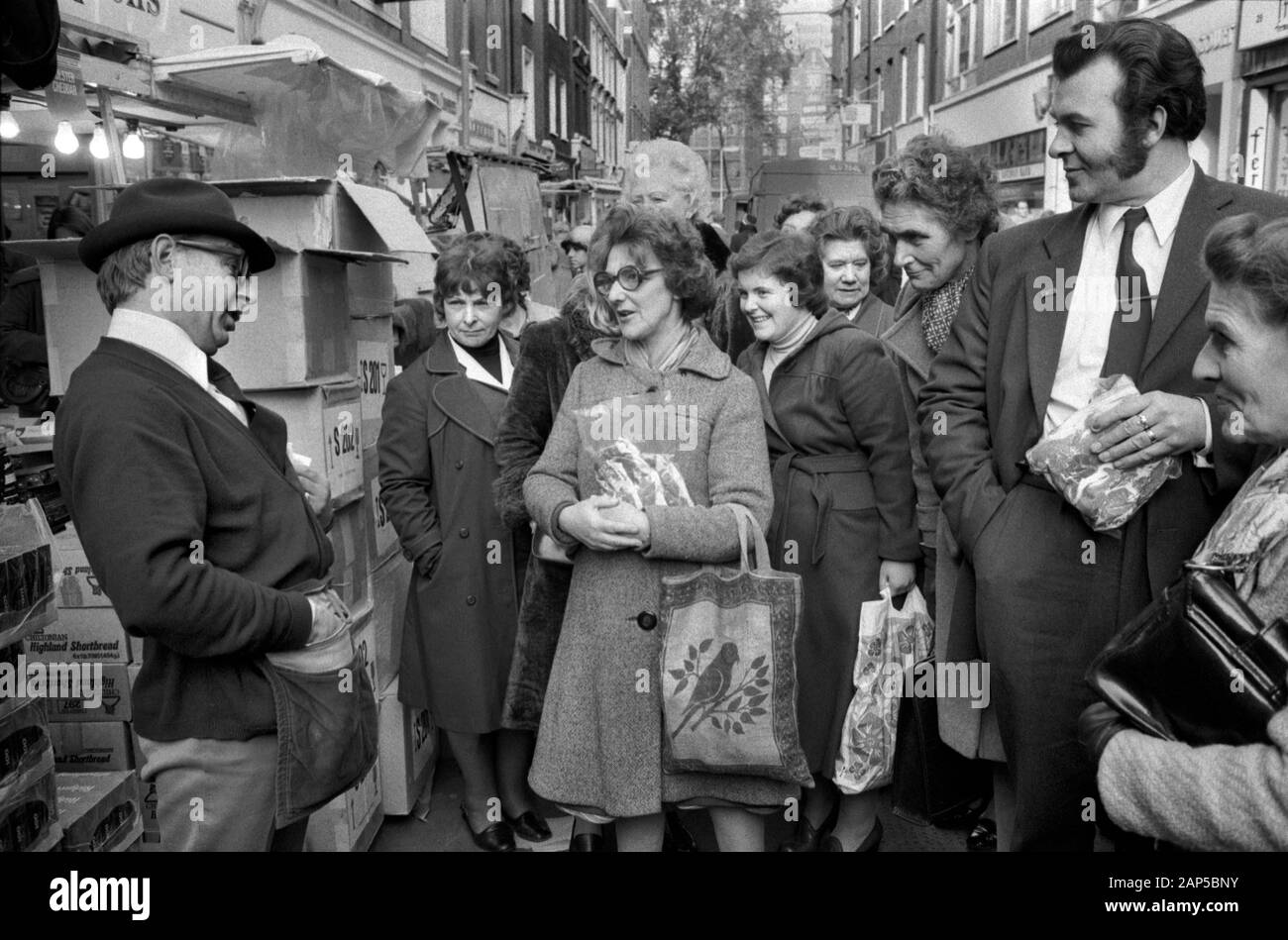 Strutton Ground Street Market, Victoria London 1970er. Markthändler, der seine Waren verkauft, zieht eine Menge an Mittagskäufern aus dem Jahr 1976 in Großbritannien HOMER SYKES ein Stockfoto