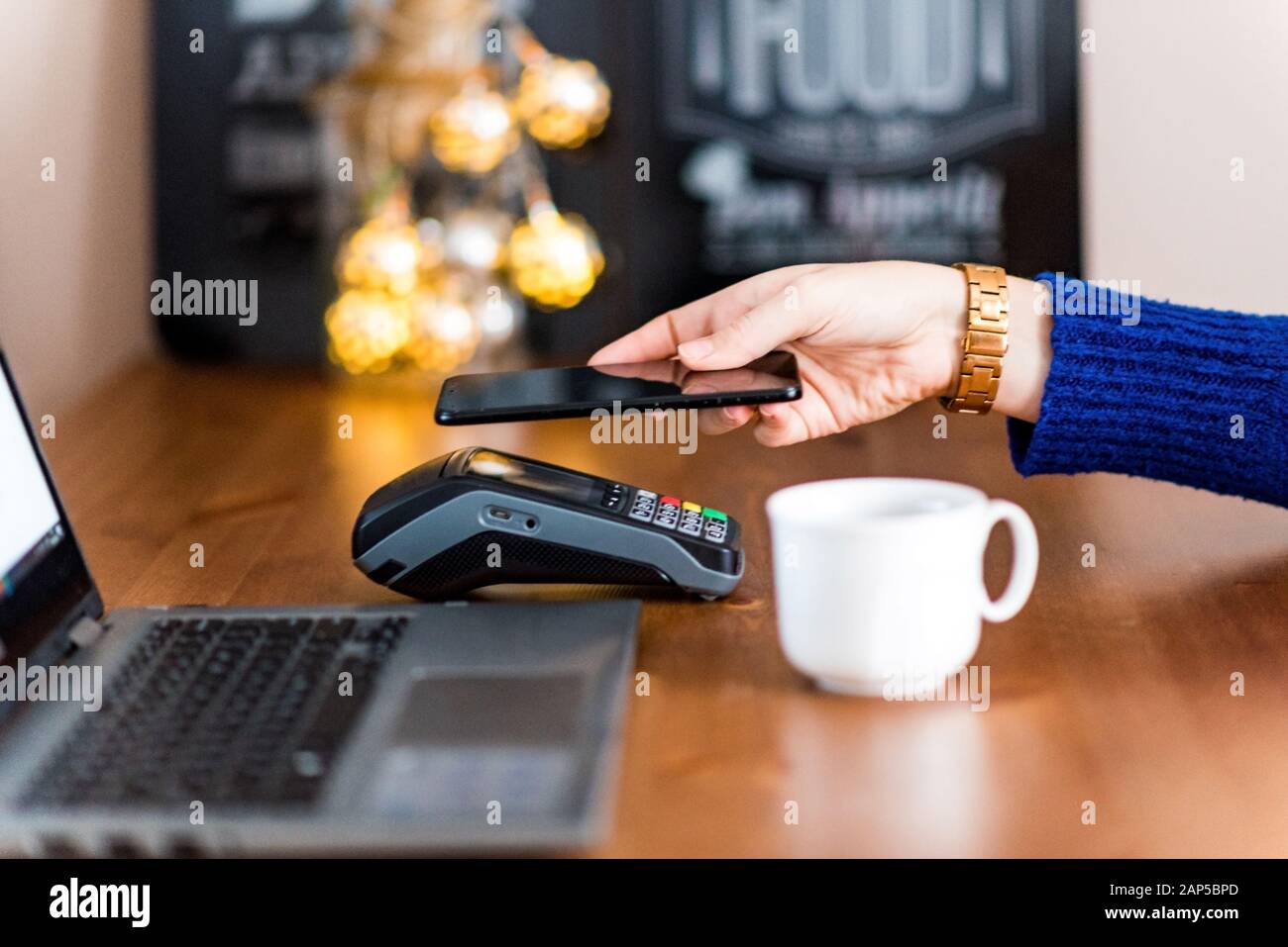 Frau, die das Terminal für kontaktloses Bezahlen über das Smartphone nutzt. Neue Technologie der NFC-Zahlung, mit dem Handy im Café bezahlen Stockfoto