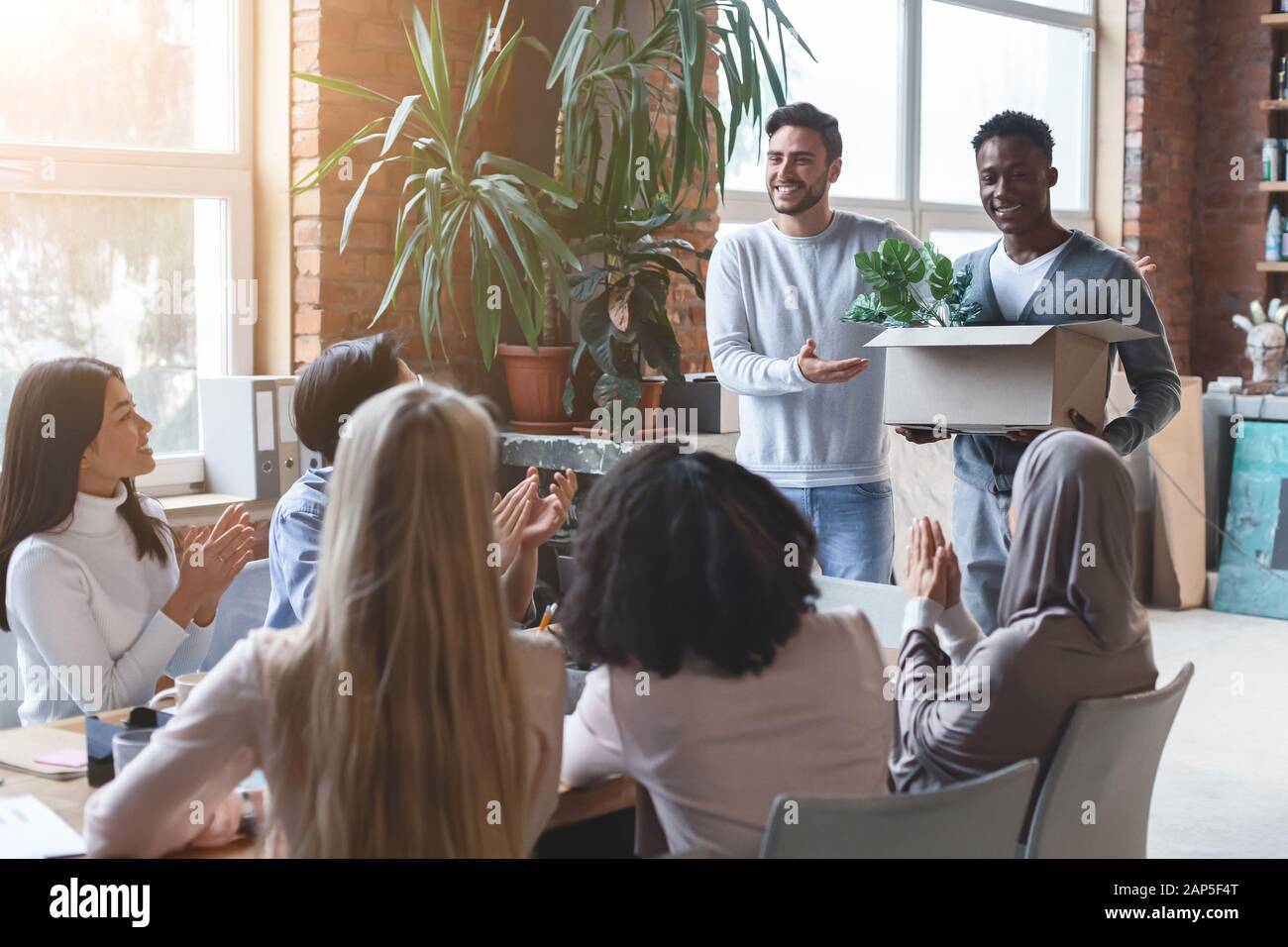 Freundliches internationales Team grüßt Neuling bei der Geschäftsbesprechung Stockfoto