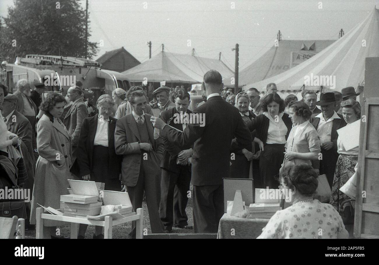 1950er Jahre, historisch, nach dem Krieg Großbritannien, auf einer Landmesse in einem Stall, der Nylone verkauft, ein geeigneter Verkäufer, der ein Paar zu den beobachtenden Besuchern zeigt, England, Großbritannien. Stockfoto