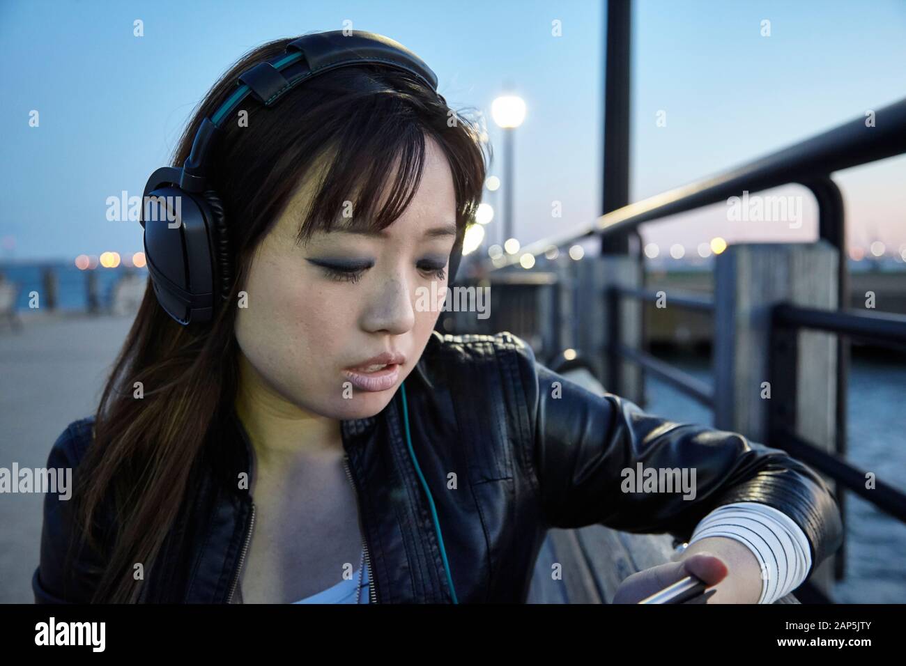 Asiatische Frau hört Kopfhörer im Park Stockfoto