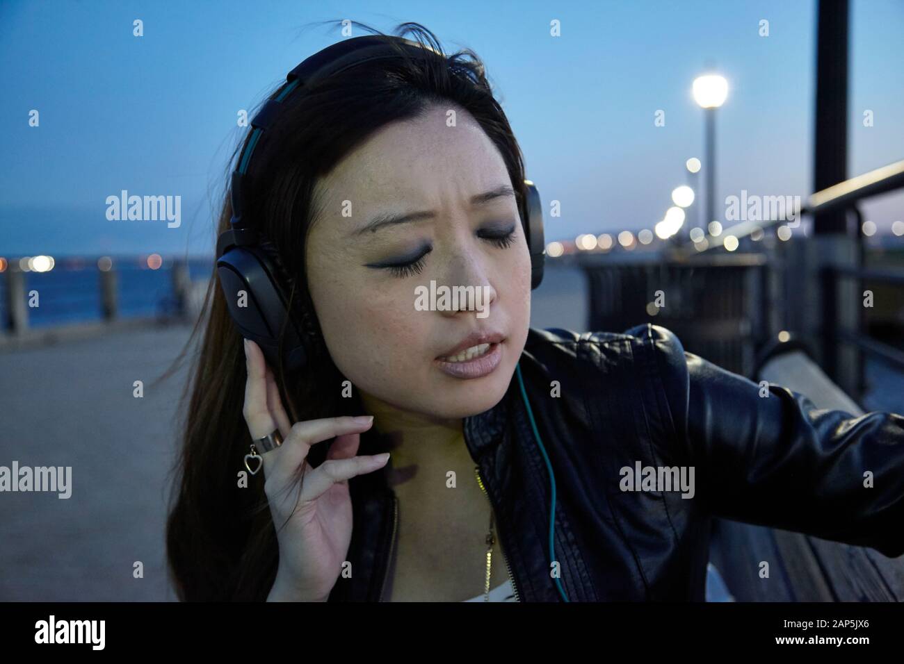 Asiatische Frau hört Kopfhörer im Park Stockfoto