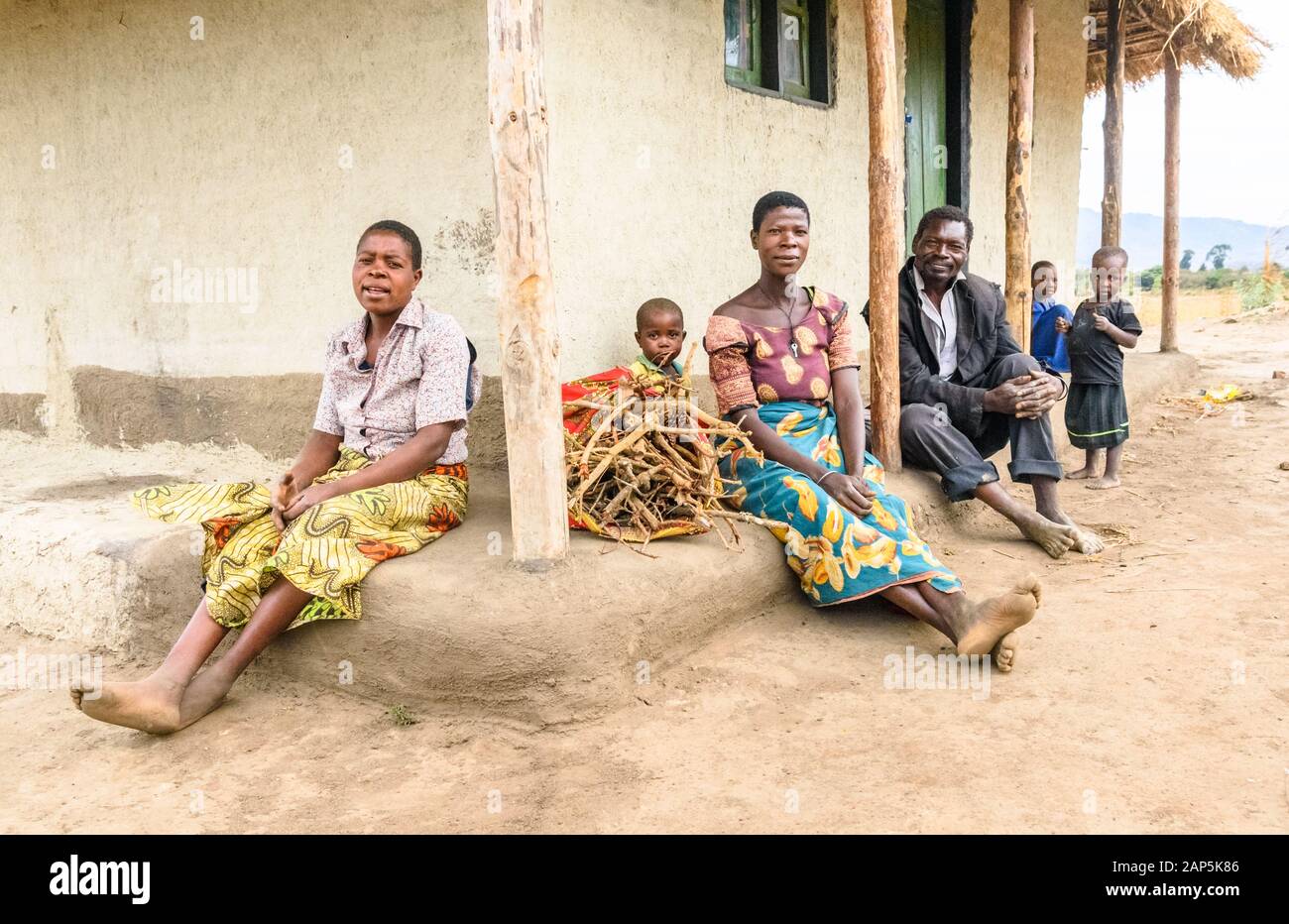 Drei Generationen einer malawianischen Familie sitzen auf der Stufe Ihrer Schlammhütte in einem Dorf Stockfoto