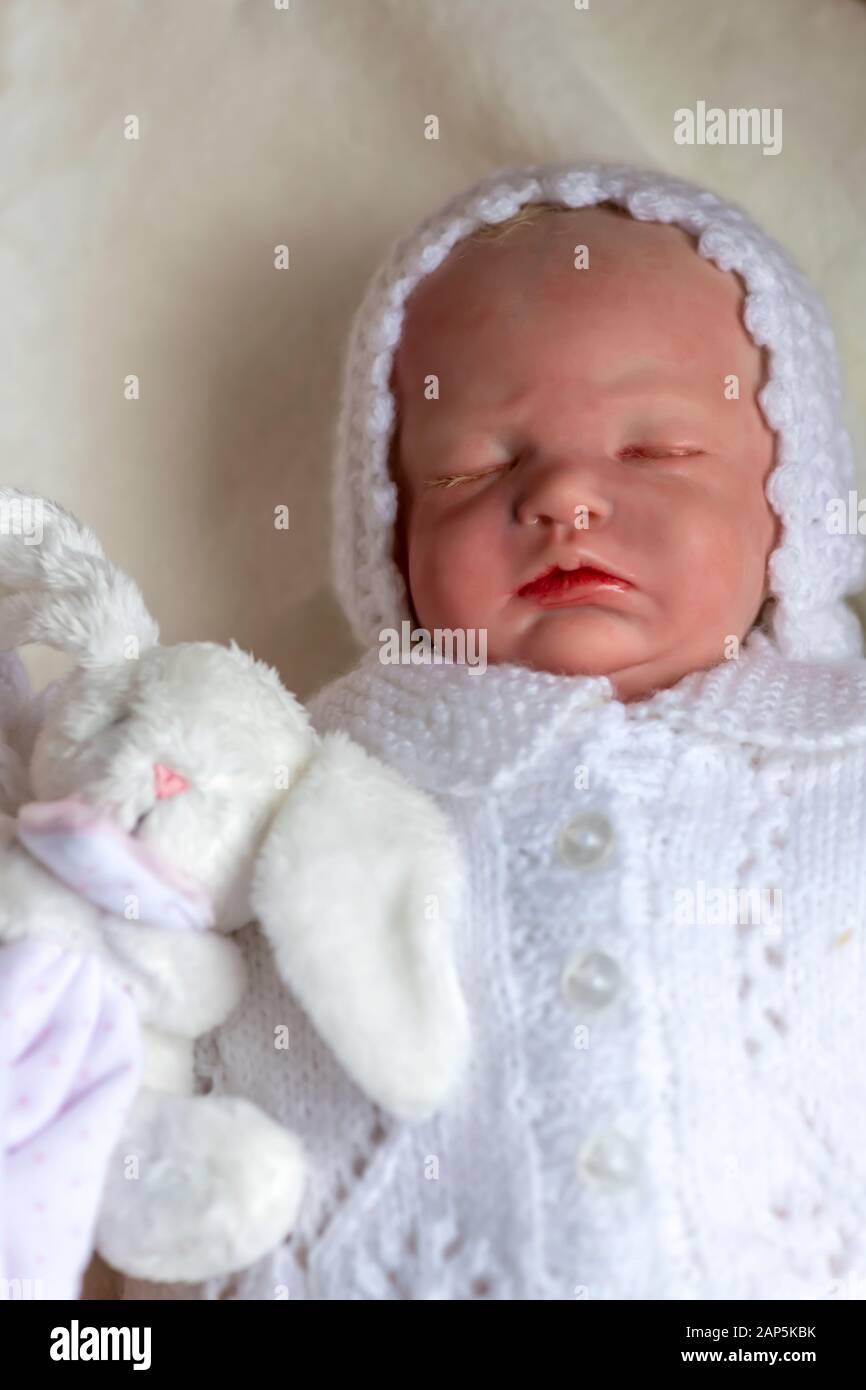 Wiedergeborene Babypuppe, die ein kleines Spielzeug hält, das sich auf den Rücken legt, selektive Fokussierung auf Werbetexte Stockfoto