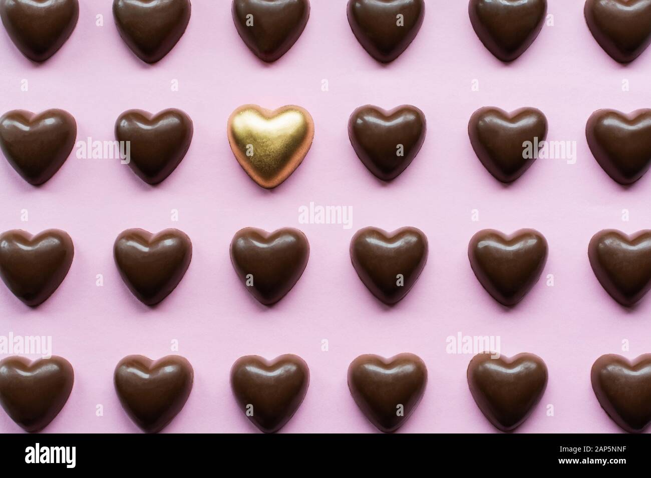Flat Lay mit Schokoladenherzen mit einer gelben Goldbonbons, die aufstehen, Stockfoto