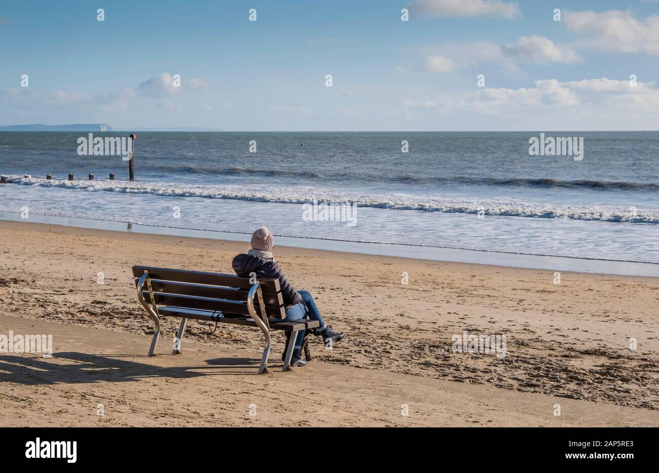 Eine Person, die allein auf der Promenade von Bournemouth sitzt und im Winter einsam aussieht Stockfoto
