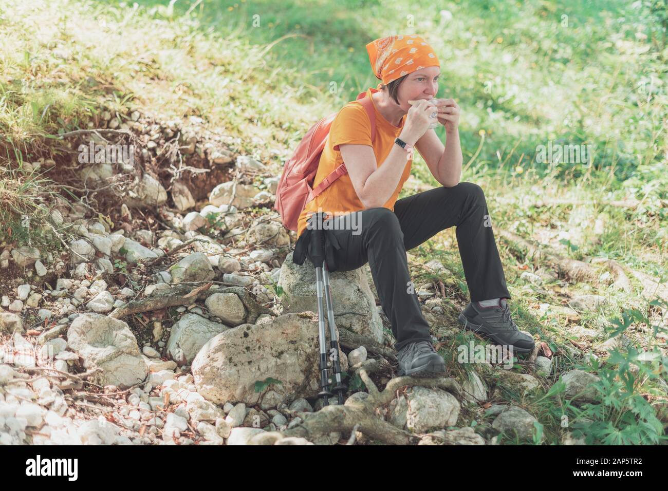 Weibliche Wanderer essen Sandwich in der Natur, eine Pause von trekking Outdoor Aktivität und Genuss Stockfoto