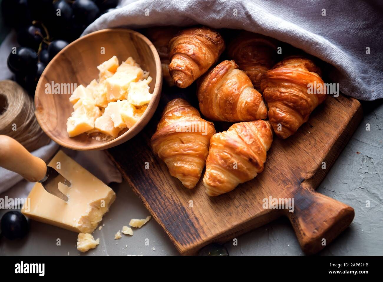 Originelle, leckere französische Croissants mit Käse und Trauben auf dem Holztisch. Butterig flockige Viennoiserie Brötchen markante Halbmond Form. Käse Stockfoto