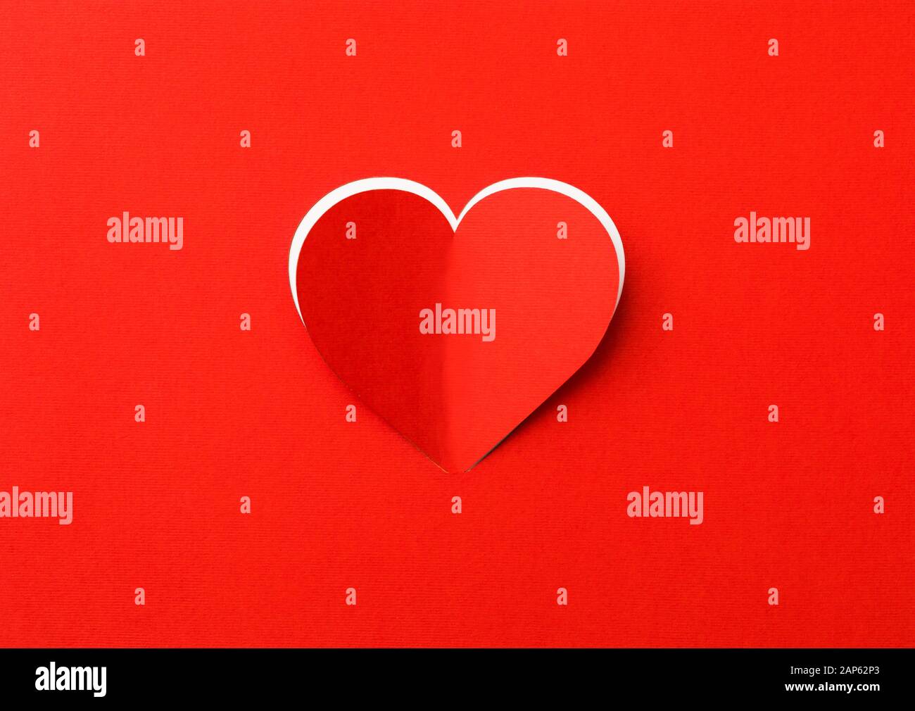 Valentines Tag Hintergrund. Ein rotes Blatt Papier mit ein ausgeschnittenes Herz. Weißer Hintergrund. Stockfoto