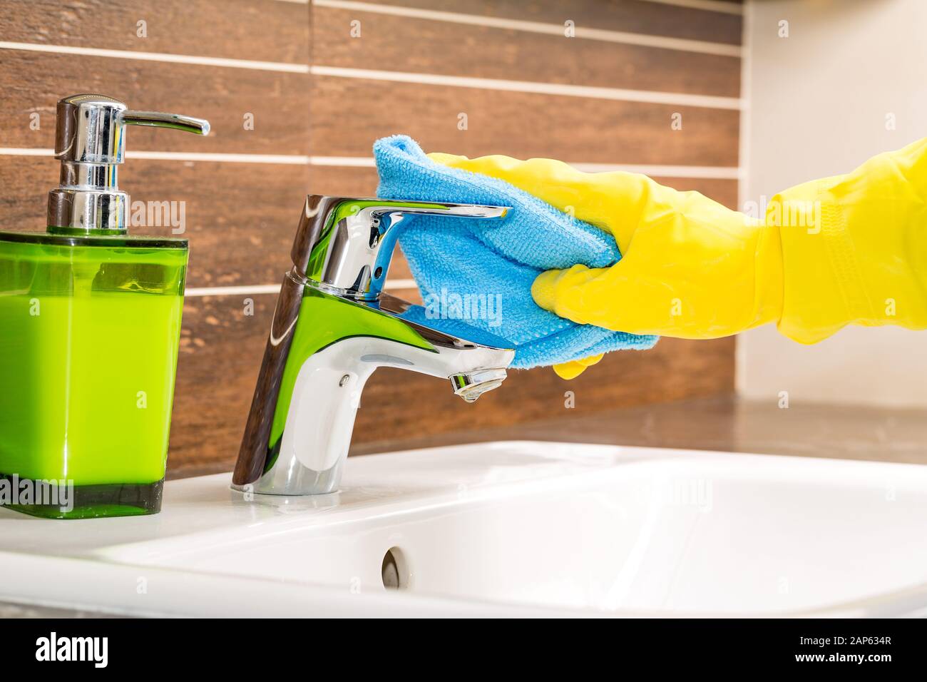 Frau tun Hausarbeiten im Badezimmer, moderne Wasserhahn reinigen. Stockfoto