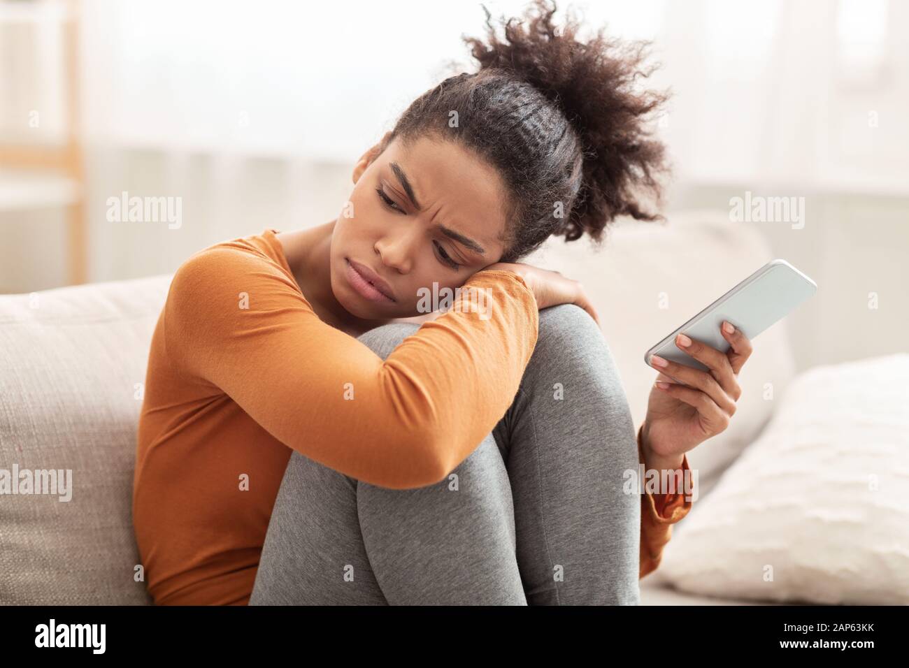 Unglücklich Millennial Girl Holding Phone Sitzt Auf Sofa Zu Hause Stockfoto