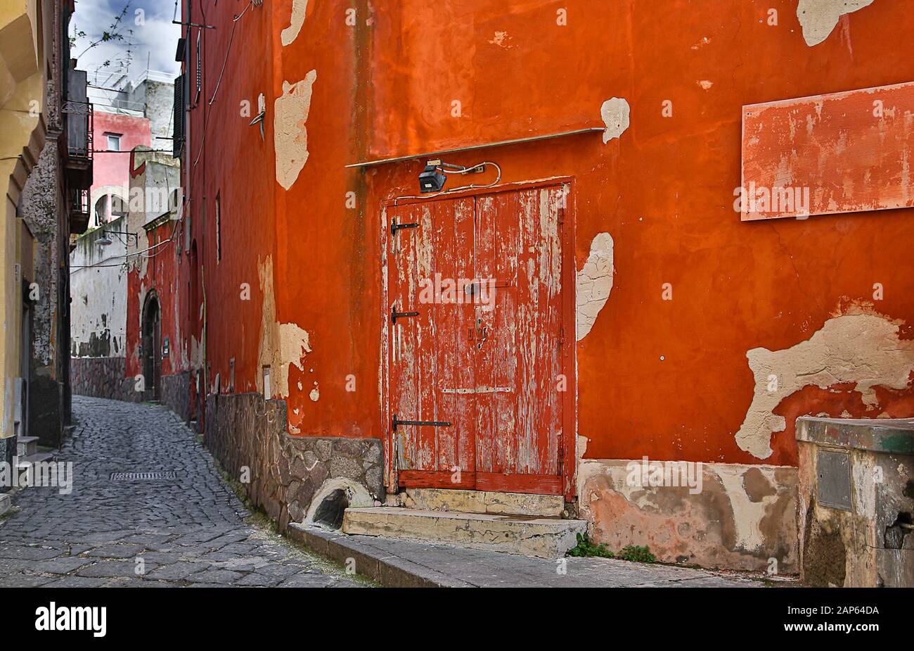 Die alte rote Tür und ihre Umgebung haben ihren eigenen Charme - Procida, Italien. Stockfoto