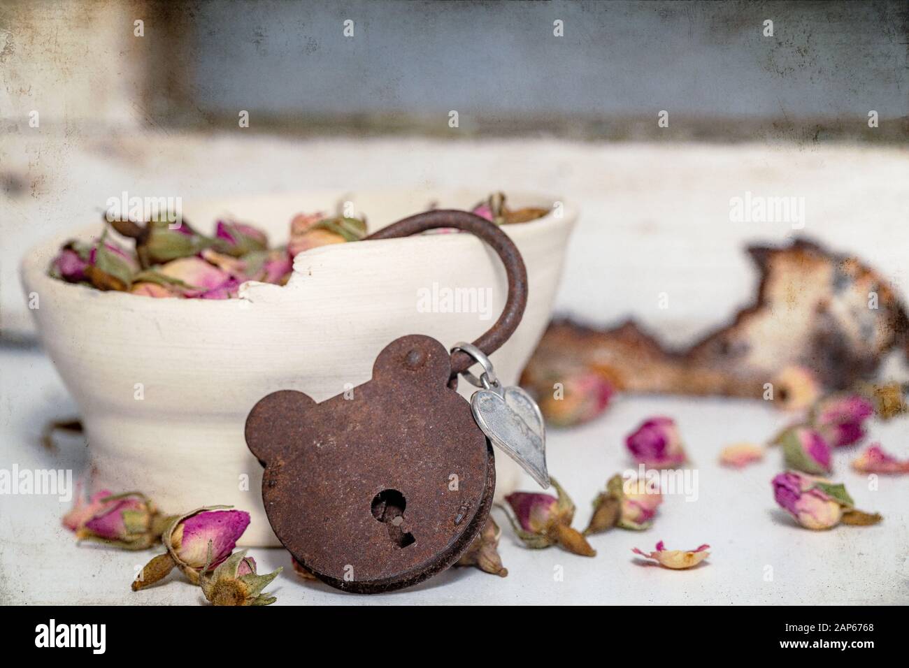 Verrostetes Teddybärschloss mit getrockneten Rosen und Keramikschale Stillleben Stockfoto