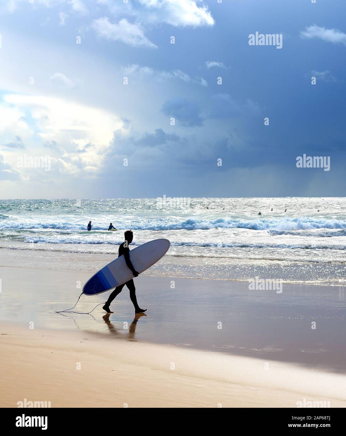 Surfer mit Surfbrett am Strand. Regen im Meer. Algarve, Portugal Stockfoto