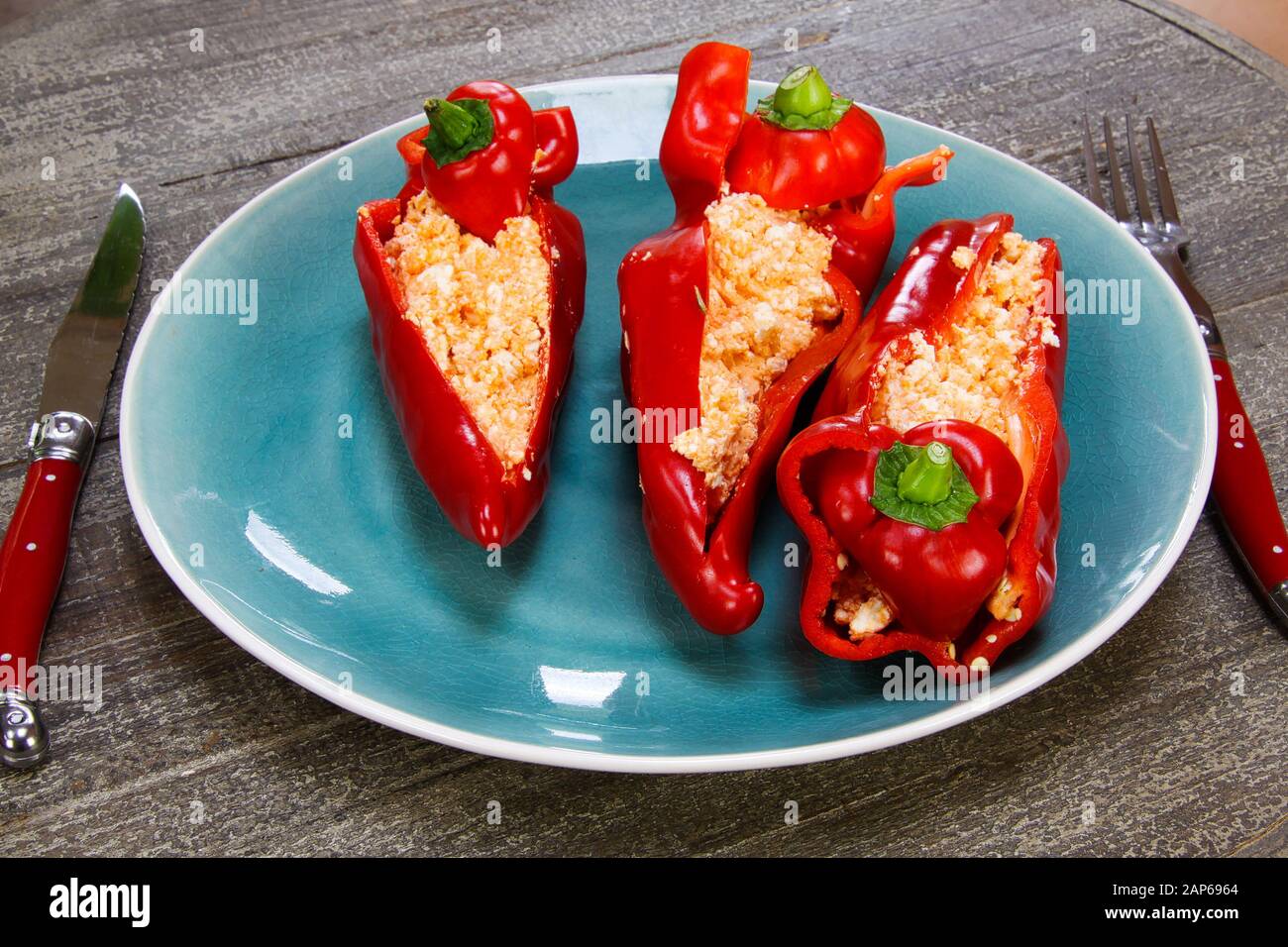 Nahaufnahme von gefüllten roten Paprikapfeffern mit Schaftkäse, gewürzt mit würzigen Chili auf Holztisch Stockfoto