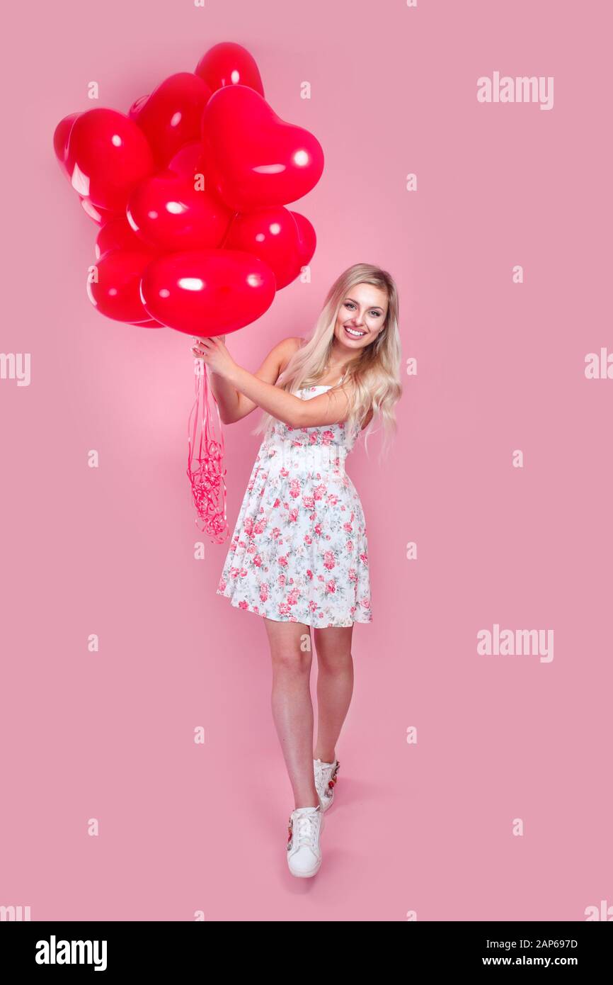 Valentinsmädchen mit roten Luftballons auf pinkfarbenem Hintergrund. Stockfoto