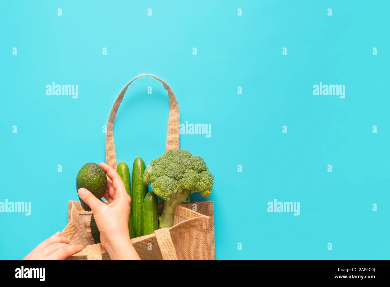 Über dem Blick auf Frau Hände Lebensmittel in wiederverwendbare Textil-Einkaufstasche auf blauem Hintergrund Stockfoto
