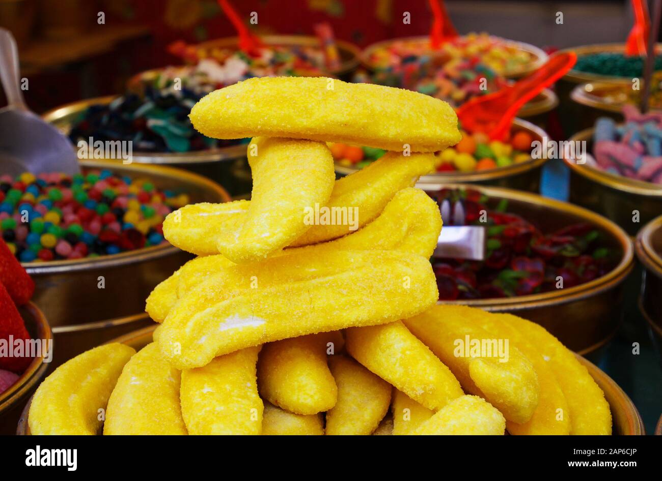 Nahaufnahme des Haufens von Süßigkeiten in Form von gelber Banane mit verschwommenen Boweln, die mit süßen Süßigkeiten auf dem französischen Markt gefüllt sind - St. Tropez, Frankreich Stockfoto