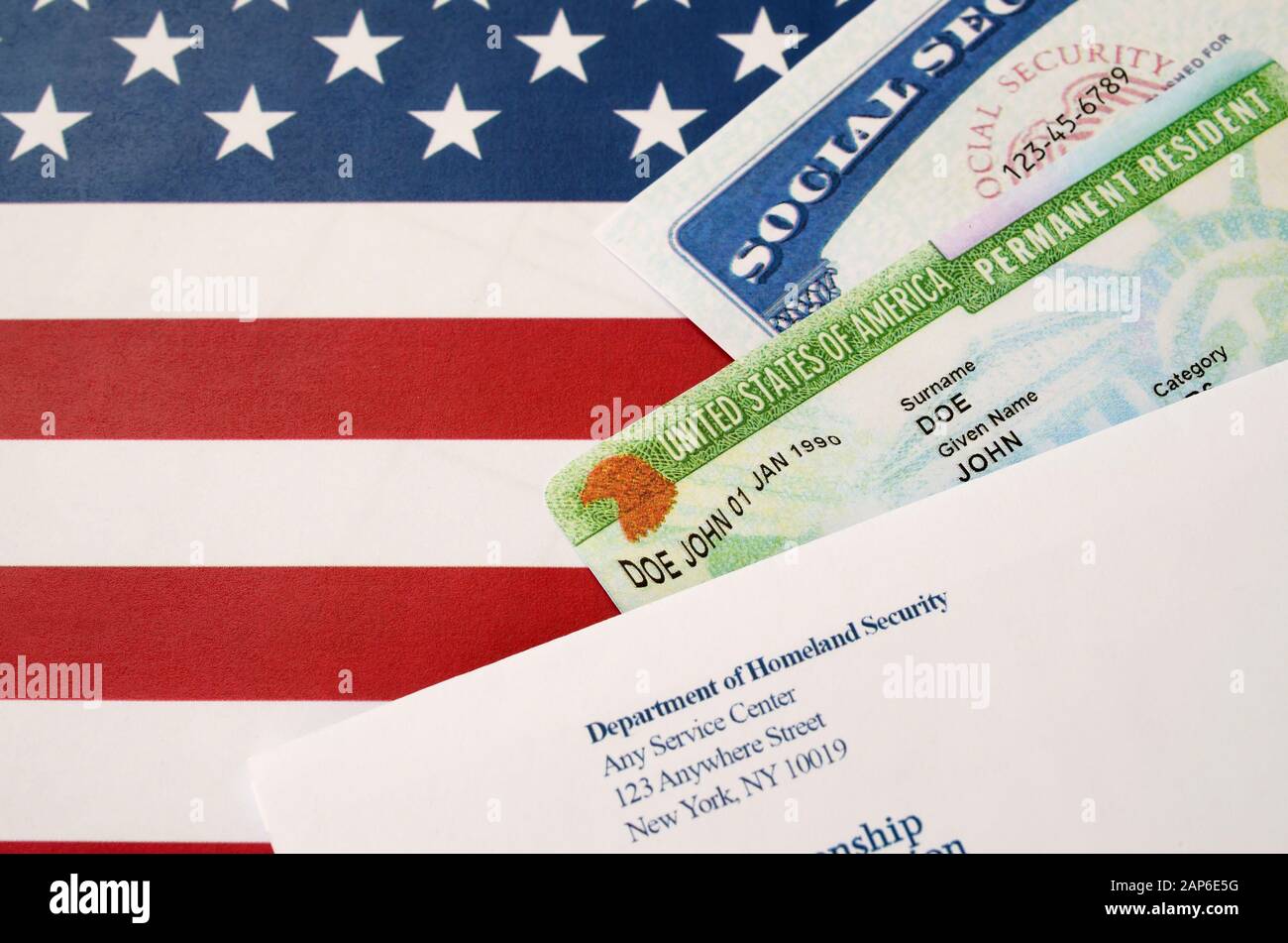 United States permanent Resident Green Card aus der DV-Lotterie mit Sozialversicherungsnummer liegt mit USCIS-Umschlag auf US-Flagge in der Nähe Stockfoto