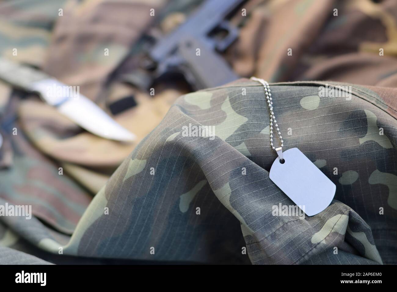 Arme-Hund-Tag-Token mit Messer und Pistole liegen auf gefaltetem, tarngrünen Stoff. Ein Set von Militärveteranen oder Trophäen-Kit für alte Aufgaben Stockfoto