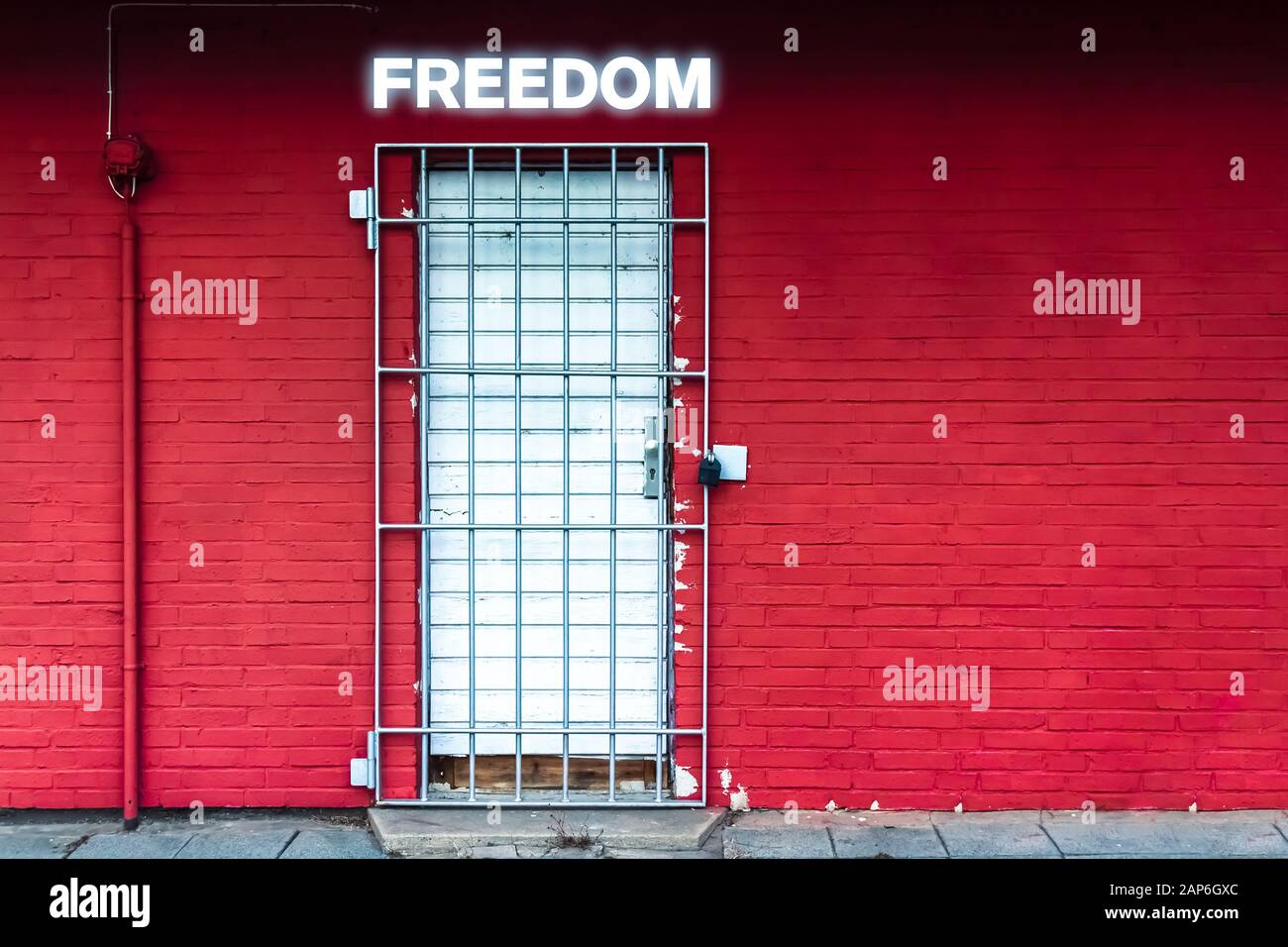 Rote Wand mit Tür, die durch Eiserne Gitter und die Freiheit des Wortes in Neon Letters gesichert ist Stockfoto