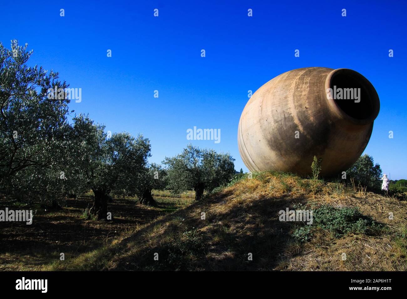 Blick über große Amphorenvase aus Ton auf Hügel auf Olivenbäumen Hain in ländlicher französischer Landschaft gegen blauen Himmel - Provence, Frankreich Stockfoto