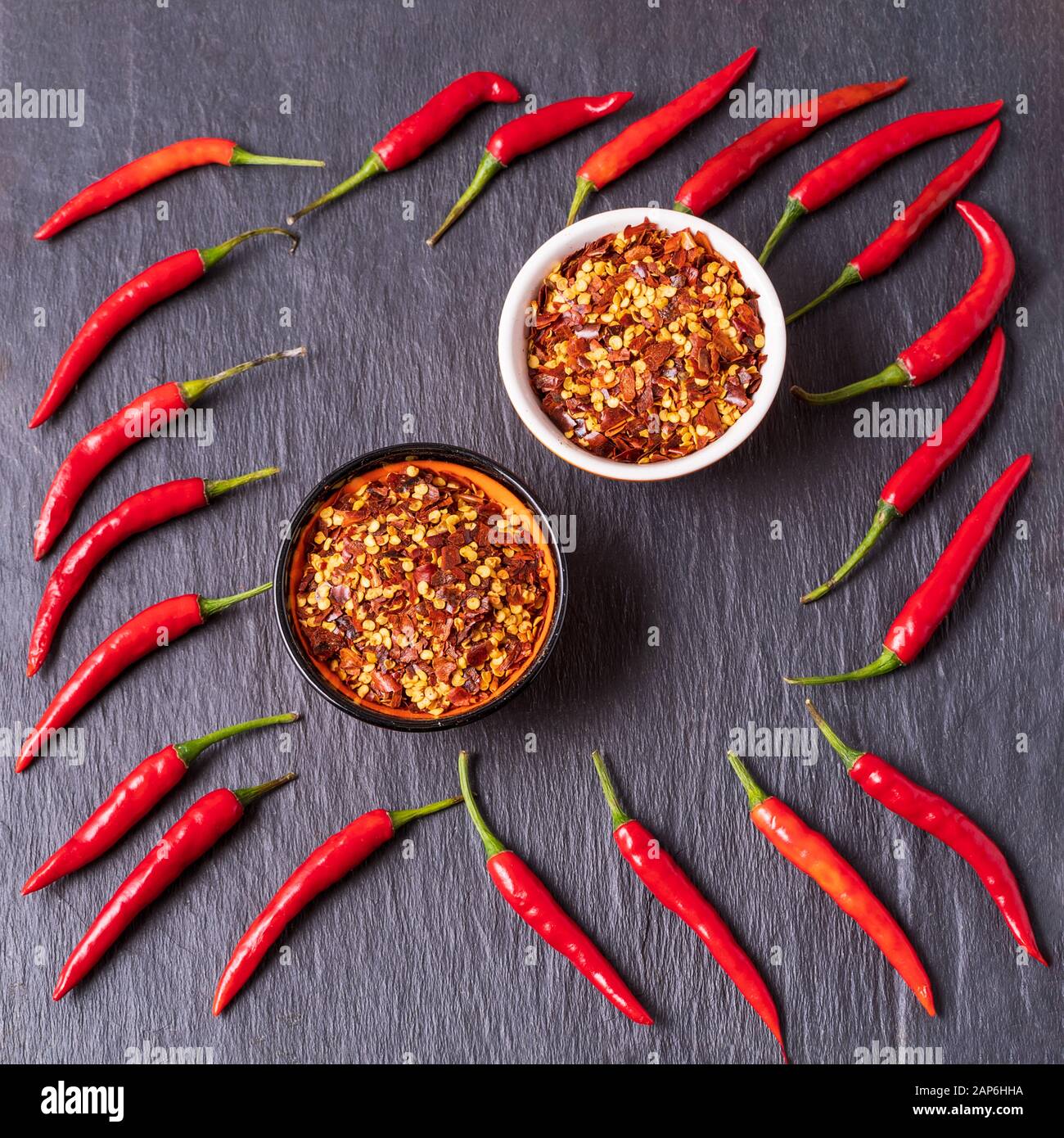 Flat Lay Zutaten für das Kochen von Soße Paste Harissa- Chili Pfeffer Gewürze und frische rote Chili Paprika, über schwarzem Hintergrund. Stockfoto