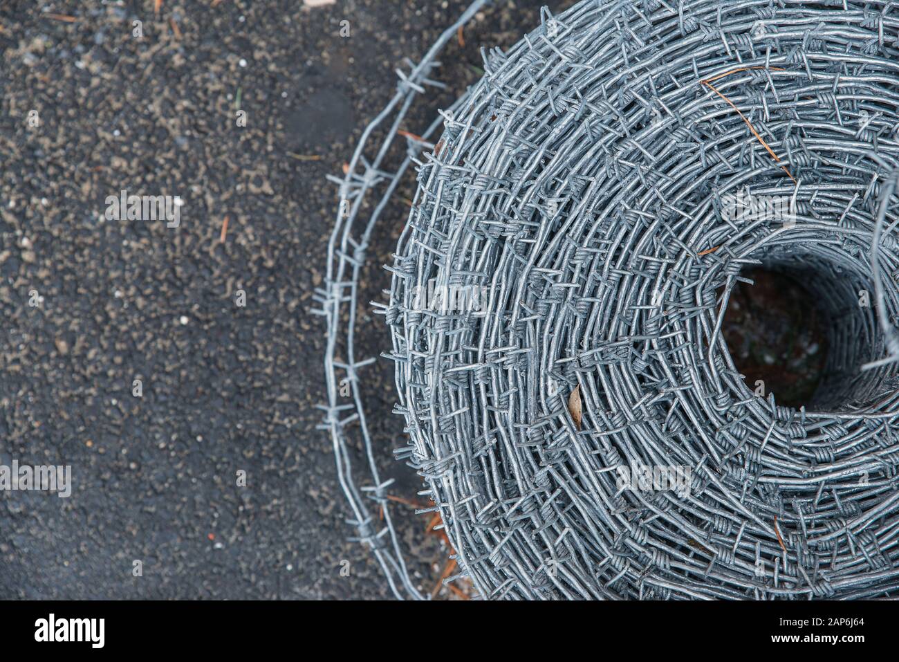 Auf einer Pfahlrolle aus glänzendem, neuem Stacheldraht zum Zaunfechten schließen. Durchsetzung von Sicherheitsvorschriften. Straftat des Gefängnis-Strafvollzugs gesperrt. Stockfoto