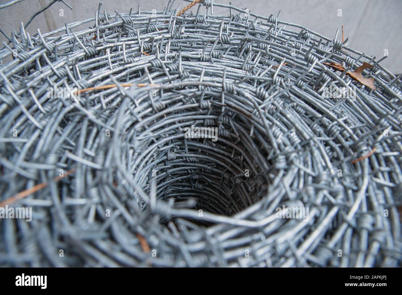 Auf einer Pfahlrolle aus glänzendem, neuem Stacheldraht zum Zaunfechten schließen. Durchsetzung von Sicherheitsvorschriften. Straftat des Gefängnis-Strafvollzugs gesperrt. Stockfoto