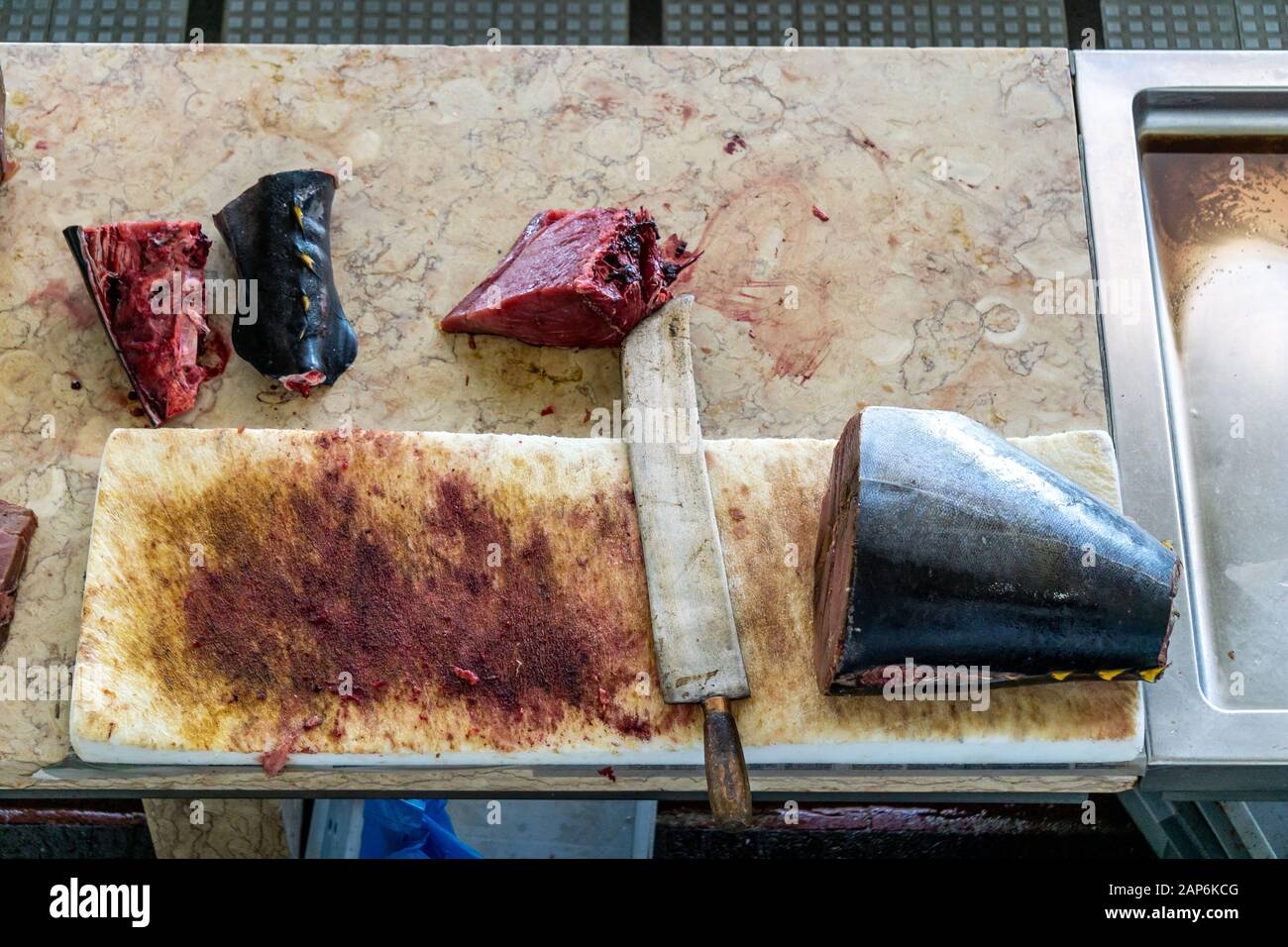 Frischer Thunfisch, in Stücke geschnitten, die auf einem Fischmarkt mit großem Messer und Blut verkauft werden können Stockfoto