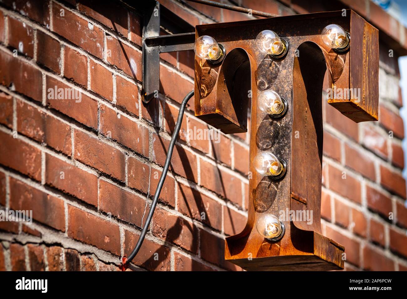 Verrosttes T-Sign auf rotem Backstein-Wandhintergrund Stockfoto