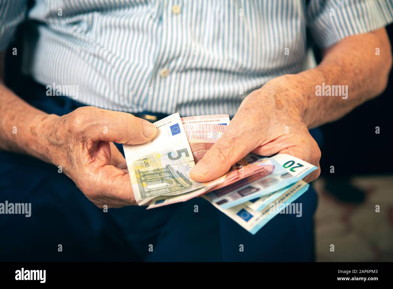 Der alte Mann, der zu Hause sitzt und ihr Geld zählt Stockfoto