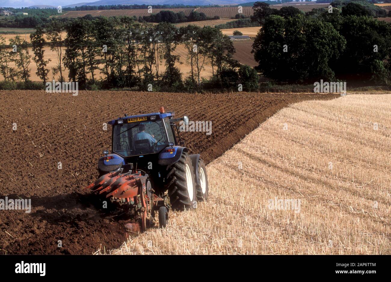 Bauern pflügen in einem Feld von Stoppeln mit einem 4 Furche reversibel in den Scottish Borders, Großbritannien Pflug. Stockfoto