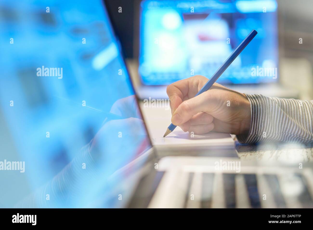 Nahaufnahme des Handarms der Frau, die mit einem Stift auf einem Dokument in der Nähe ihres Computer-Laptop-pcs in ihrem Heimbüro auf ihrem Arbeitsplatz arbeitet Stockfoto