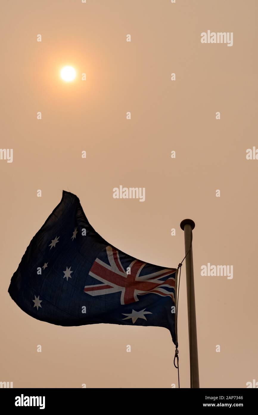 Australische Flagge, die mit Sonne gegen den duftigen Himmel fliegt Stockfoto