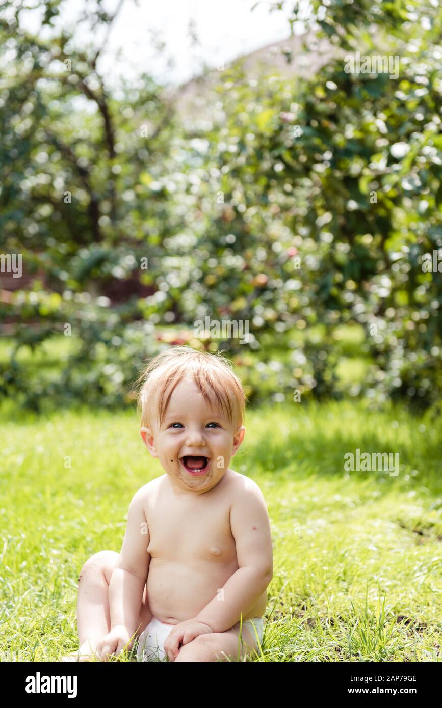 Kleiner Junge sitzt auf dem Gras und lacht Stockfoto