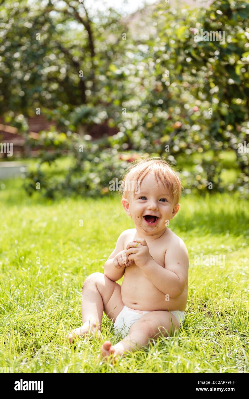 Kleiner Junge sitzt auf dem Gras und lacht Stockfoto