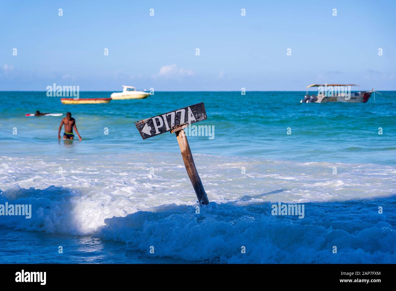 Zeigerpizzen auf einem Holzpfosten im Meerwasser am tropischen Strand der Insel Sansibar, Tansania, Ostafrika. Reise- und Urlaubskonzept Stockfoto