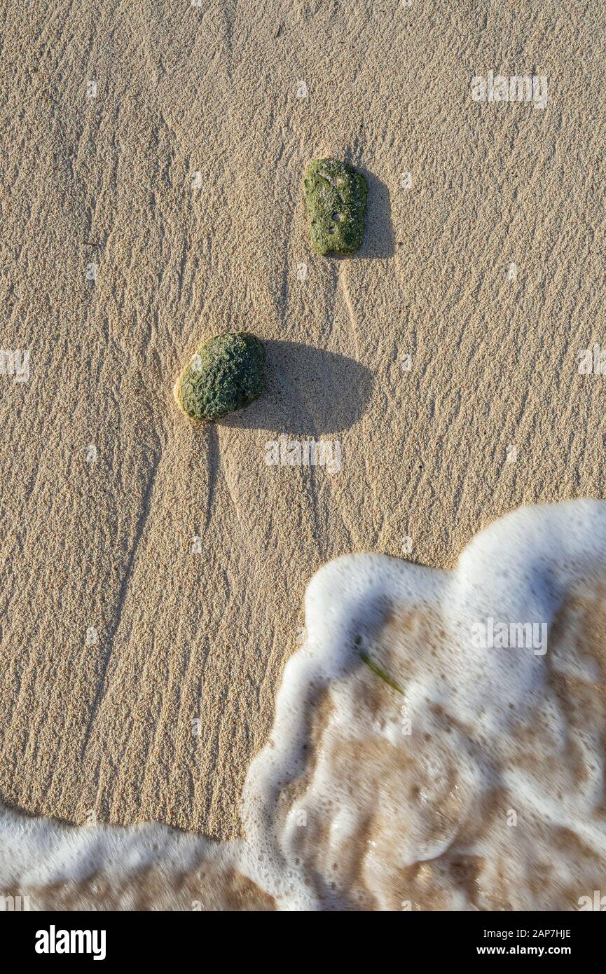Muster im Sand, der von Wellen und Felsen gebildet wird Stockfoto